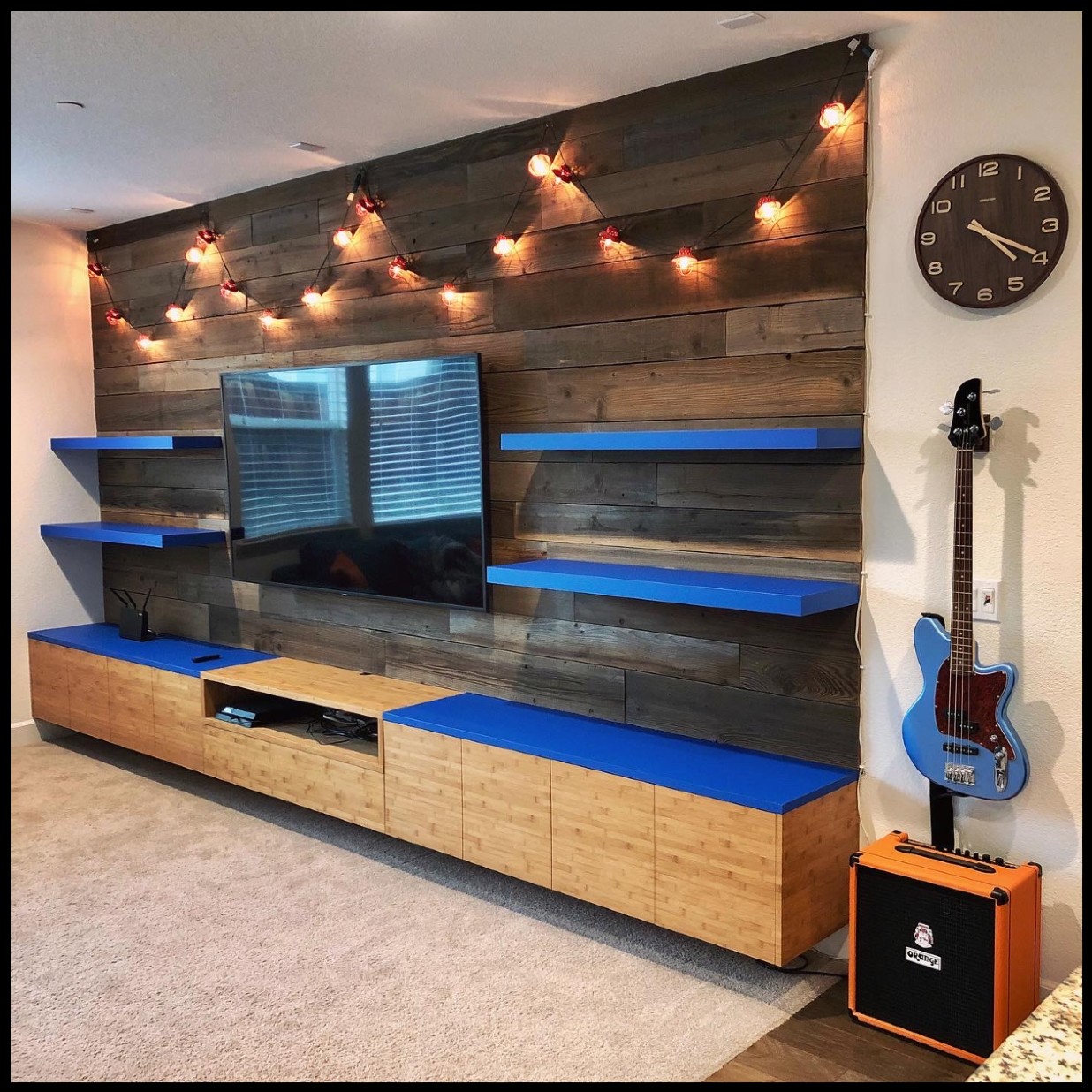 wall with storage, tv, bright blue shelves and guitar
